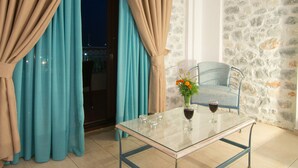 A room with a glass table, a chair, and curtains. - Vathi Hotel (East Mani)