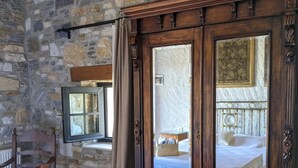 A room with a stone wall, a wooden wardrobe, a bed with a blue bedspread, and a chair. - Bahab Guest House (Soke)