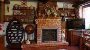 A cozy living room with a brick fireplace, wine rack, and a television. - B&B Villa Sans Souci (Civitavecchia)