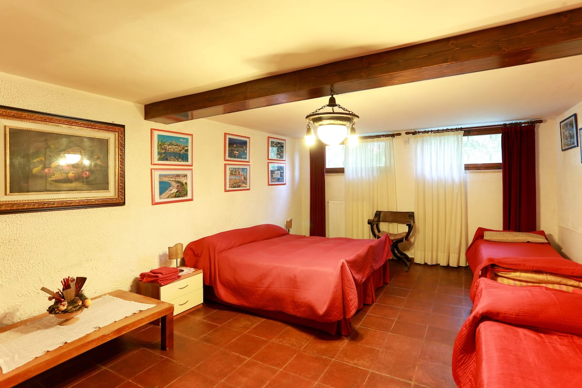Quarto de hotel com duas camas, um banco de madeira, uma mesa pequena com uma tigela decorativa e um quadro na parede.