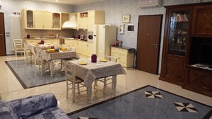 Amplia sala de estar con comedor, sofá y cocina al fondo.