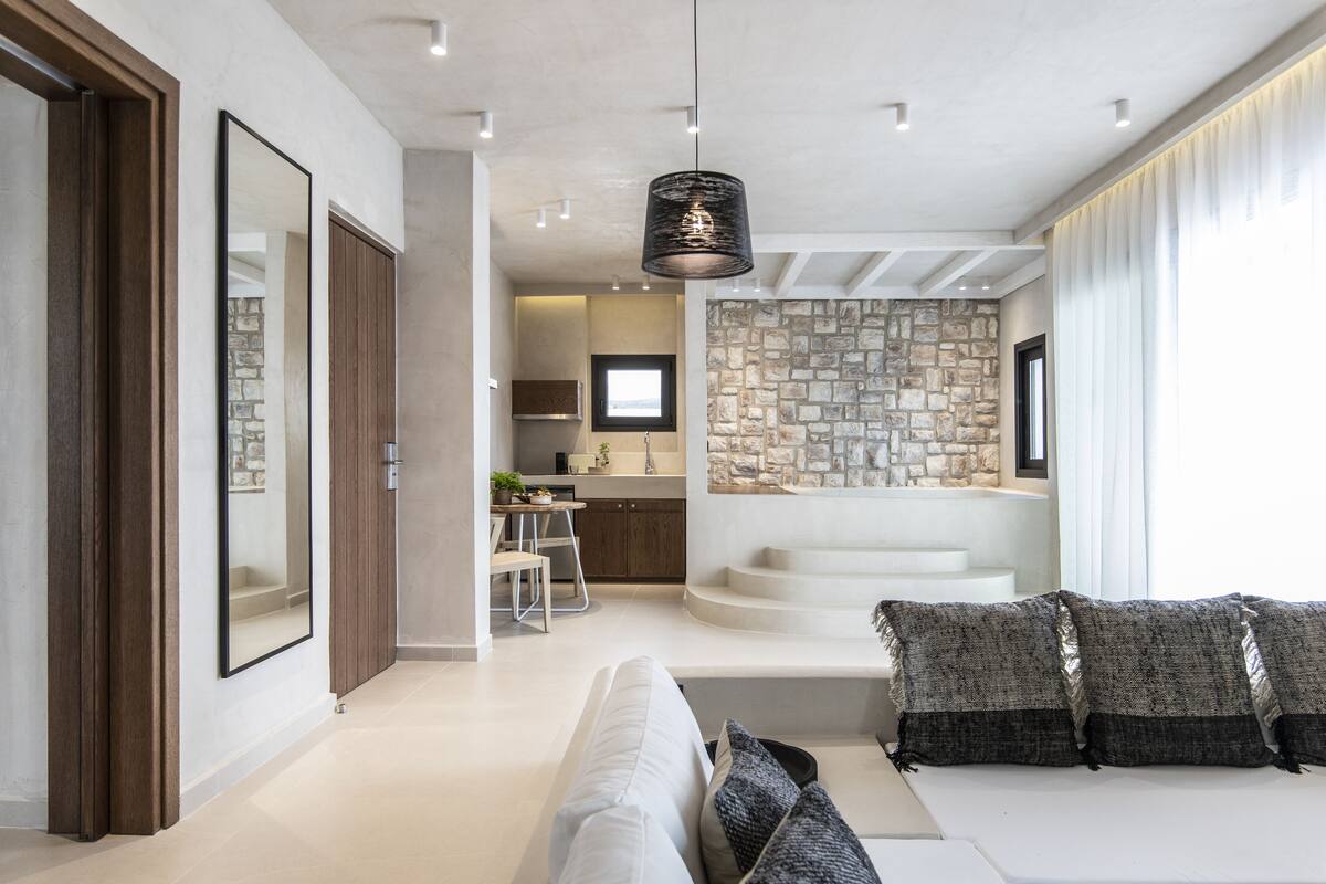 A modern interior with a living area, kitchen, and a stone wall.