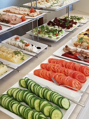 A buffet with various food items including sliced tomatoes, cucumbers, and different types of meats and cheeses. - Marina Mielno z widokiem na Jezioro (Mielno)