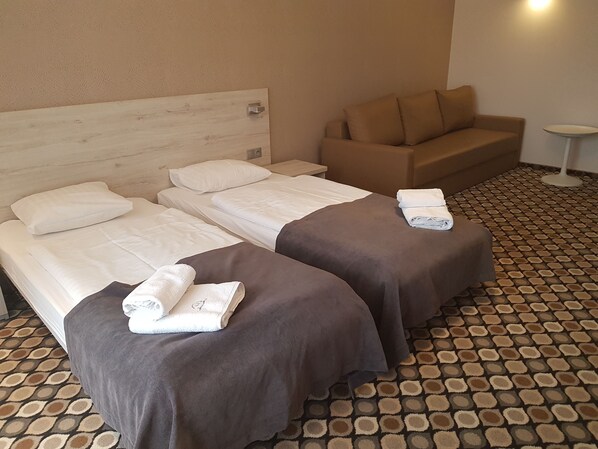 A hotel room with two beds, a sofa, and a small table.