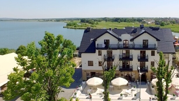 A two-story building with a balcony, outdoor seating area, and a view of a lake.