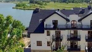 A two-story building with a balcony, outdoor seating area, and a view of a river.