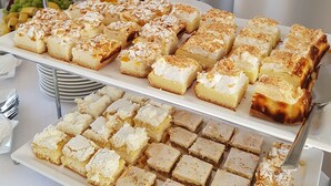 A dessert buffet with various cakes and pastries, a candle holder, and a fruit platter.
