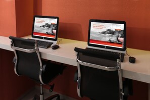 Dois laptops HP sobre uma mesa com cadeiras de escritório pretas.