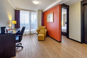 Ein Hotelzimmer mit Schreibtisch, Stuhl, Sofa und Bett.