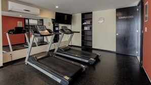 A fitness room with treadmills, a TV, a clock, and a door labeled "GIMNASIO". - Comfort Inn San Luis Potosi (San Luis Potosi)