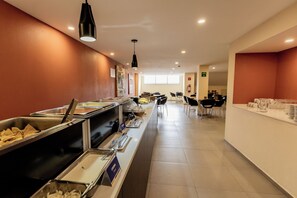 A buffet area with various food options, a seating area with chairs, and a counter with a water dispenser. - Comfort Inn San Luis Potosi (San Luis Potosi)