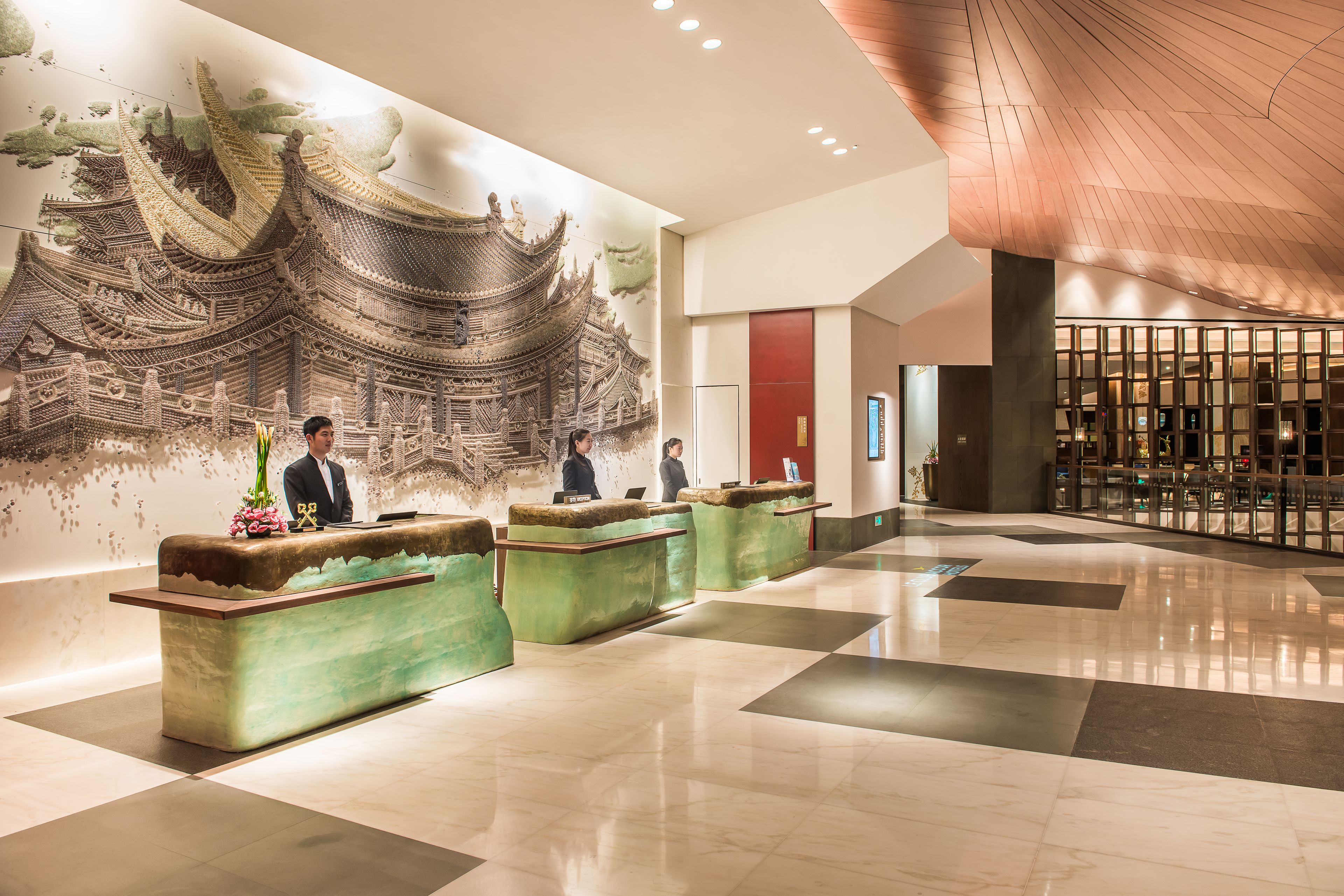 Un área de recepción con un mural de arquitectura china tradicional, un mostrador de recepción y un diseño de interiores moderno.