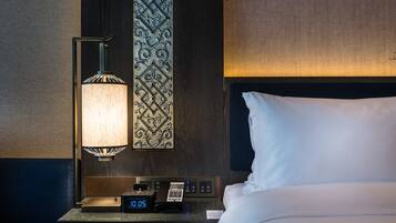 Une chambre d’hôtel avec un lit, une table de chevet dotée d’une horloge numérique, une lampe et un panneau décoratif au mur.