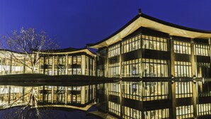 Een modern gebouw met grote glasramen en een spiegeling in het water.