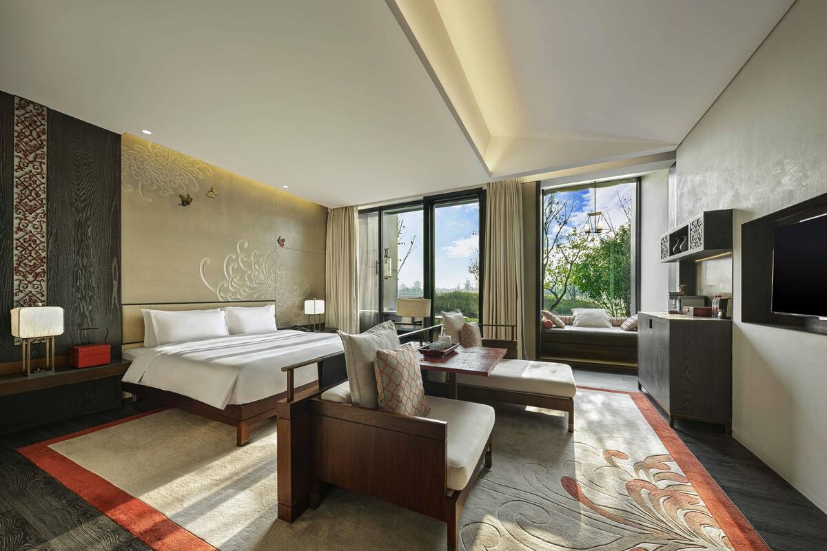 Una habitación de hotel moderna con una cama grande, un sofá, un escritorio y un televisor.
