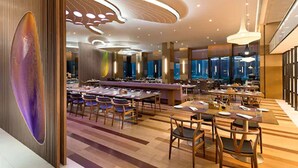 Een modern restaurant met een centrale bar, meerdere eettafels en stoelen.