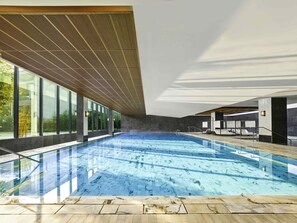 Una piscina techada, sillones reclinables de piscina