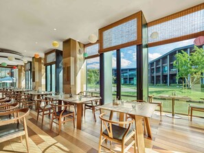 Enjoy meals in a dining area with large windows offering views of a lush outdoor space.