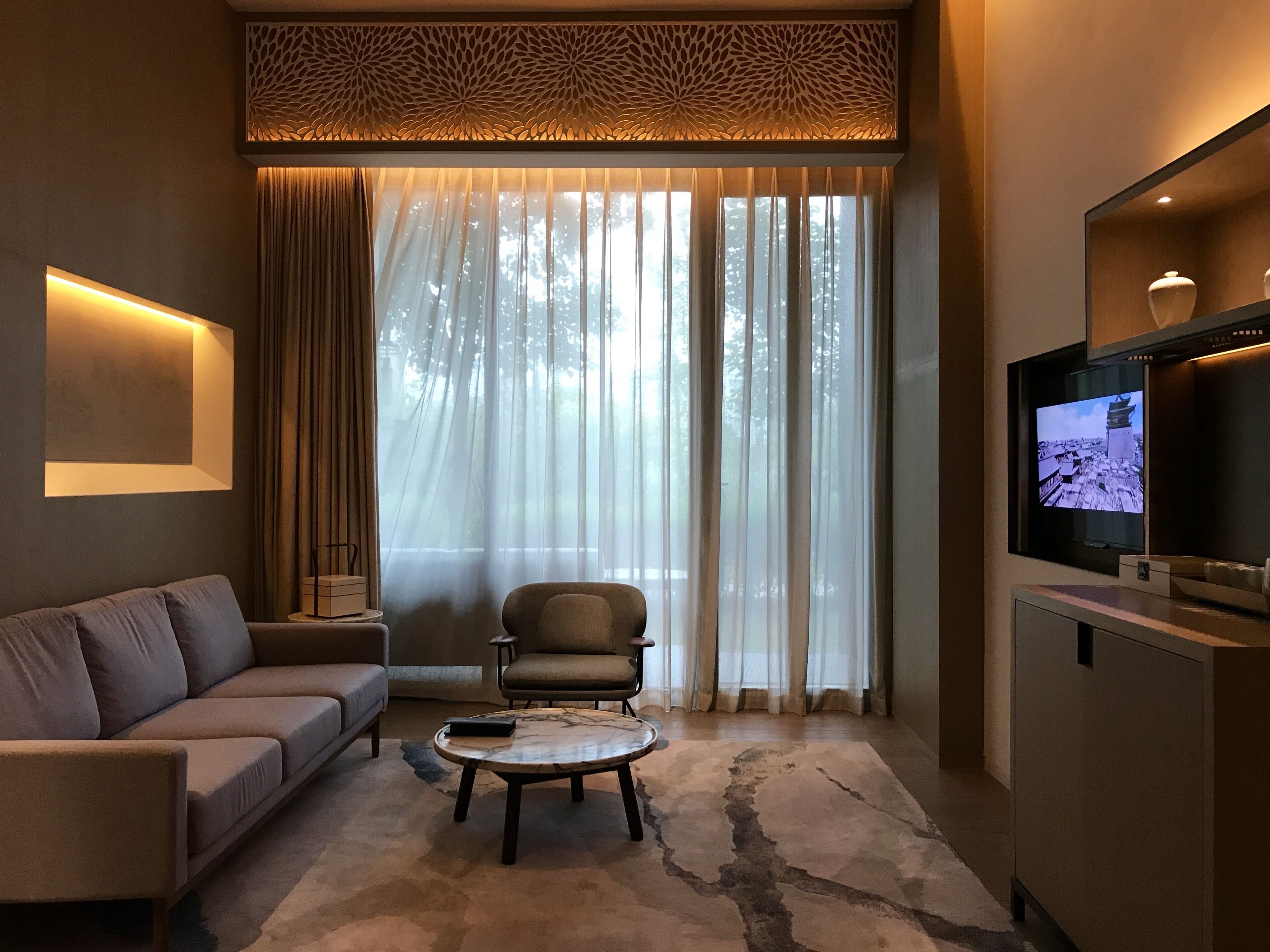 Una sala moderna con sofá, sillón, mesa de centro y televisor sobre un mueble.