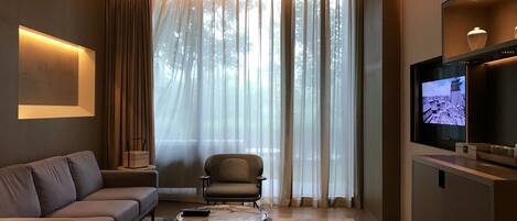 Una sala moderna con sofá, sillón, mesa de centro y televisor sobre un mueble.