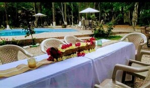 A poolside dining area with a table set for two, surrounded by chairs, and a pool in the background. - Hotel Campestre Santa Ana (Santa Ana)