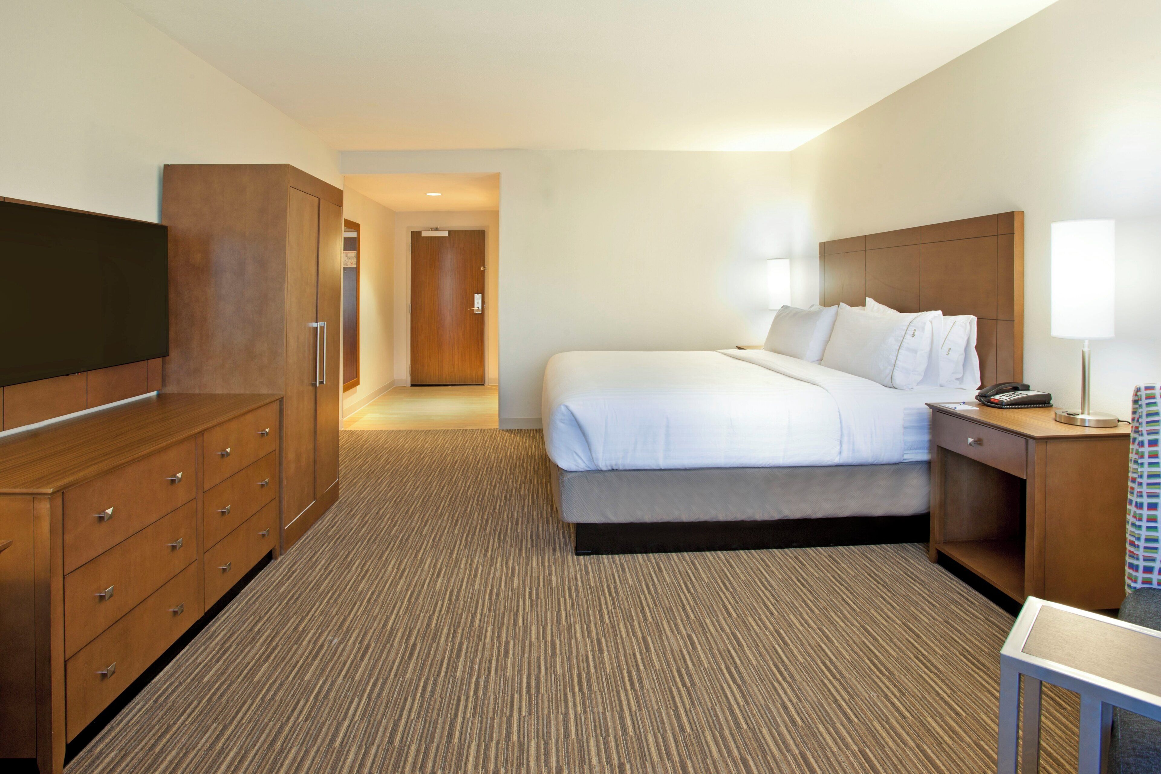Una habitación de hotel con cama, televisión, escritorio y armario.