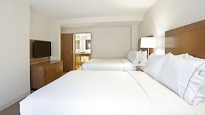 Une chambre d’hôtel avec deux lits, une télévision, une commode et un miroir.