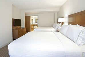 Une chambre d’hôtel avec deux lits, une télévision, une commode et un miroir.