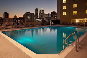 A rooftop pool with lounge chairs and a city skyline in the background. - Holiday Inn Express & Suites Austin Downtown - University by IHG (Austin)
