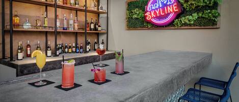 A bar area with shelves of liquor bottles, a neon sign, and bar stools.
