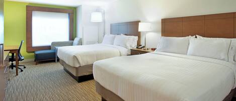 A hotel room with two beds, a desk, a chair, a lamp, and a window.
