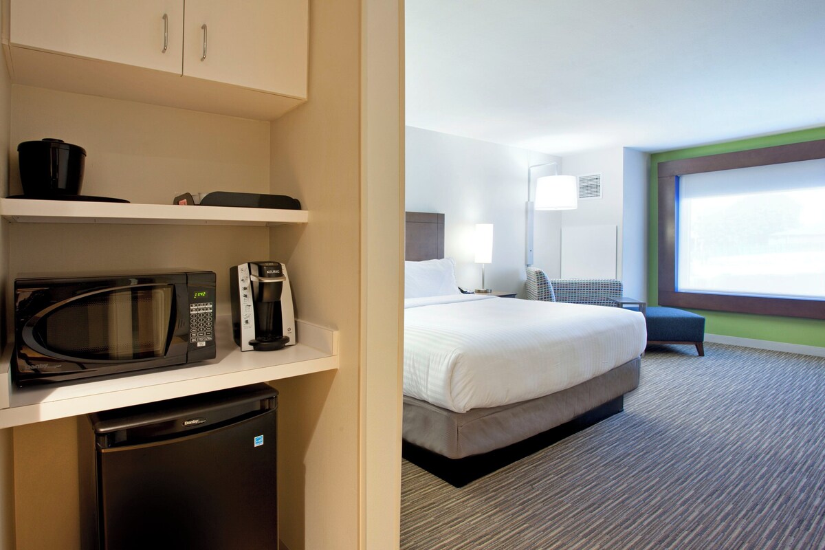 Une chambre d’hôtel avec un lit, une table de chevet, une lampe et une vue sur l’extérieur.