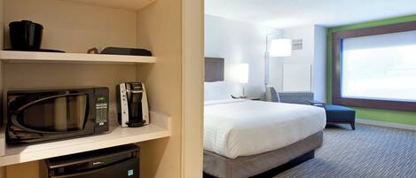 A hotel room with a bed, bedside table, lamp, and a view of the outdoors.