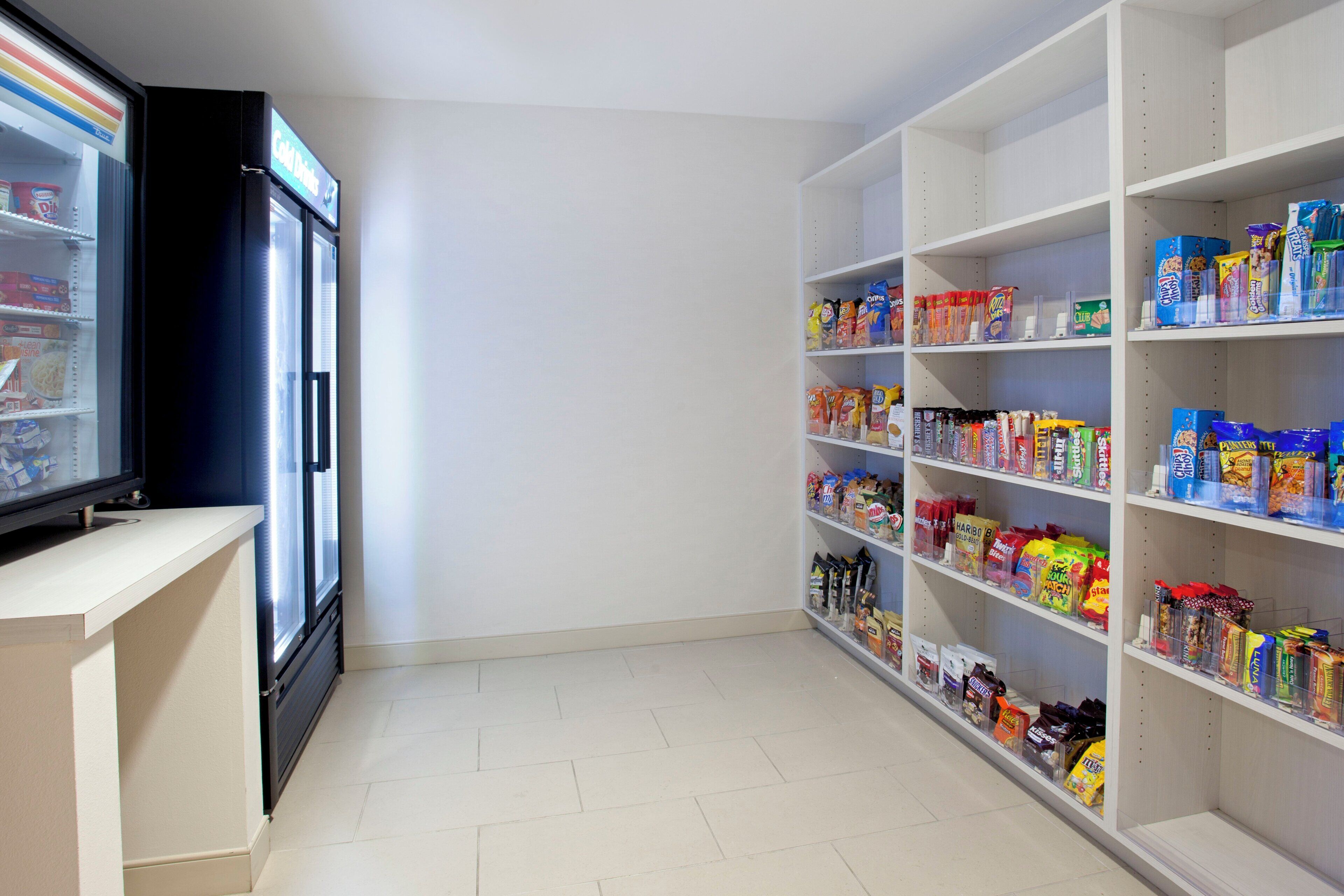 A snack aisle with various packaged goods and a refrigerator on the left.
