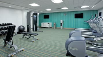 A gym with exercise equipment, including treadmills, a bench press, and dumbbells.