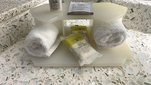 Un meuble-lavabo de salle de bain avec des articles de toilette, notamment un flacon de lotion, un savon et deux serviettes.