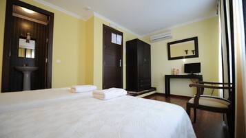 Une chambre d’hôtel comprenant un lit, un lavabo, une armoire, un bureau avec une chaise et un téléviseur.