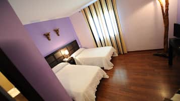 Une chambre d’hôtel avec deux lits, un plancher en bois, une télévision et un rideau.