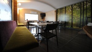 A modern room with a curved ceiling, a large window with a forest view, a flat-screen TV, and a dining area with chairs and a table.
