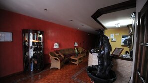 A lobby with red walls, wicker furniture, a glass display case, and a black statue.