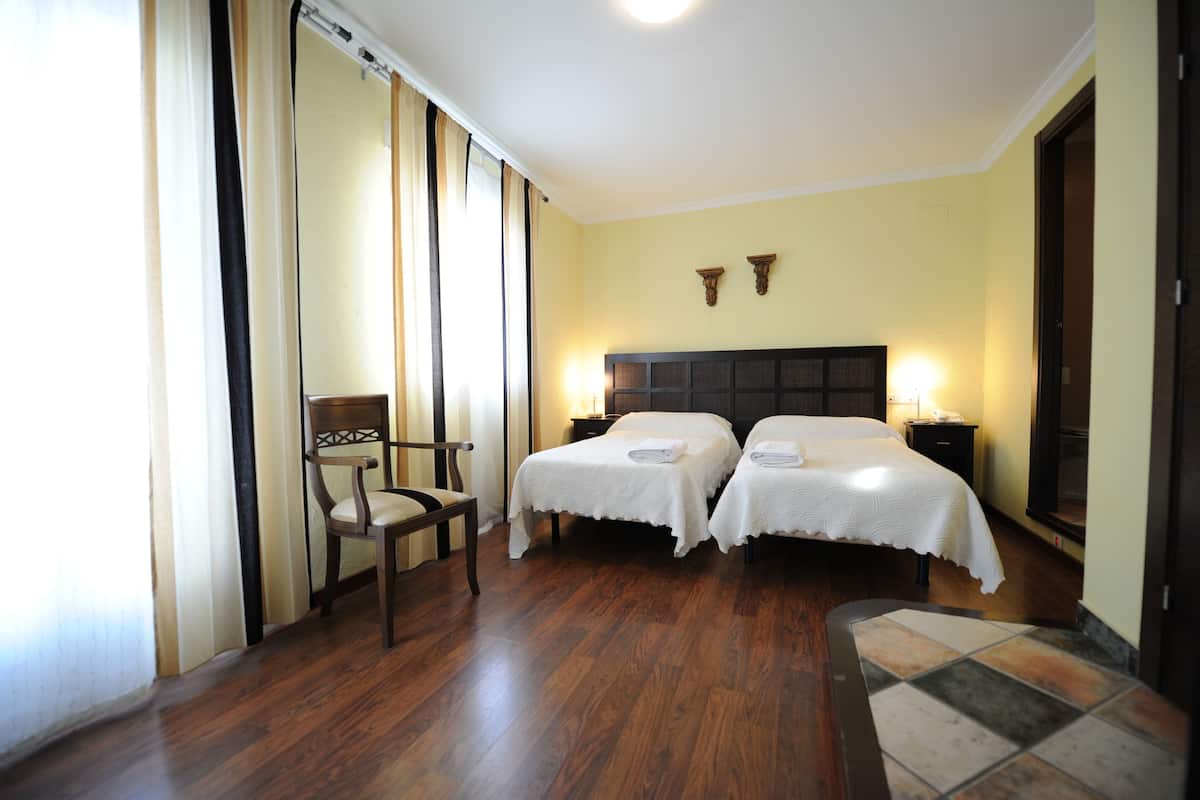 Een hotelkamer met twee bedden, een stoel en een kleine tafel.