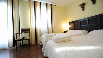 A hotel room with two beds, a chair, and a nightstand with a lamp.