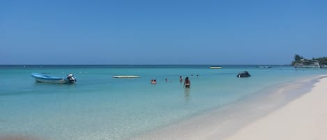 Privéstrand vlakbij, wit zand, ligstoelen aan het strand, parasols