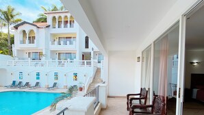 Un balcon avec une piscine, un coin repas et une vue sur un immeuble à plusieurs étages doté de balcons.