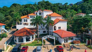 Un hôtel avec un toit recouvert de tuiles rouges, une cour intérieure et une enseigne indiquant « West Bay Colonial Hotel ».