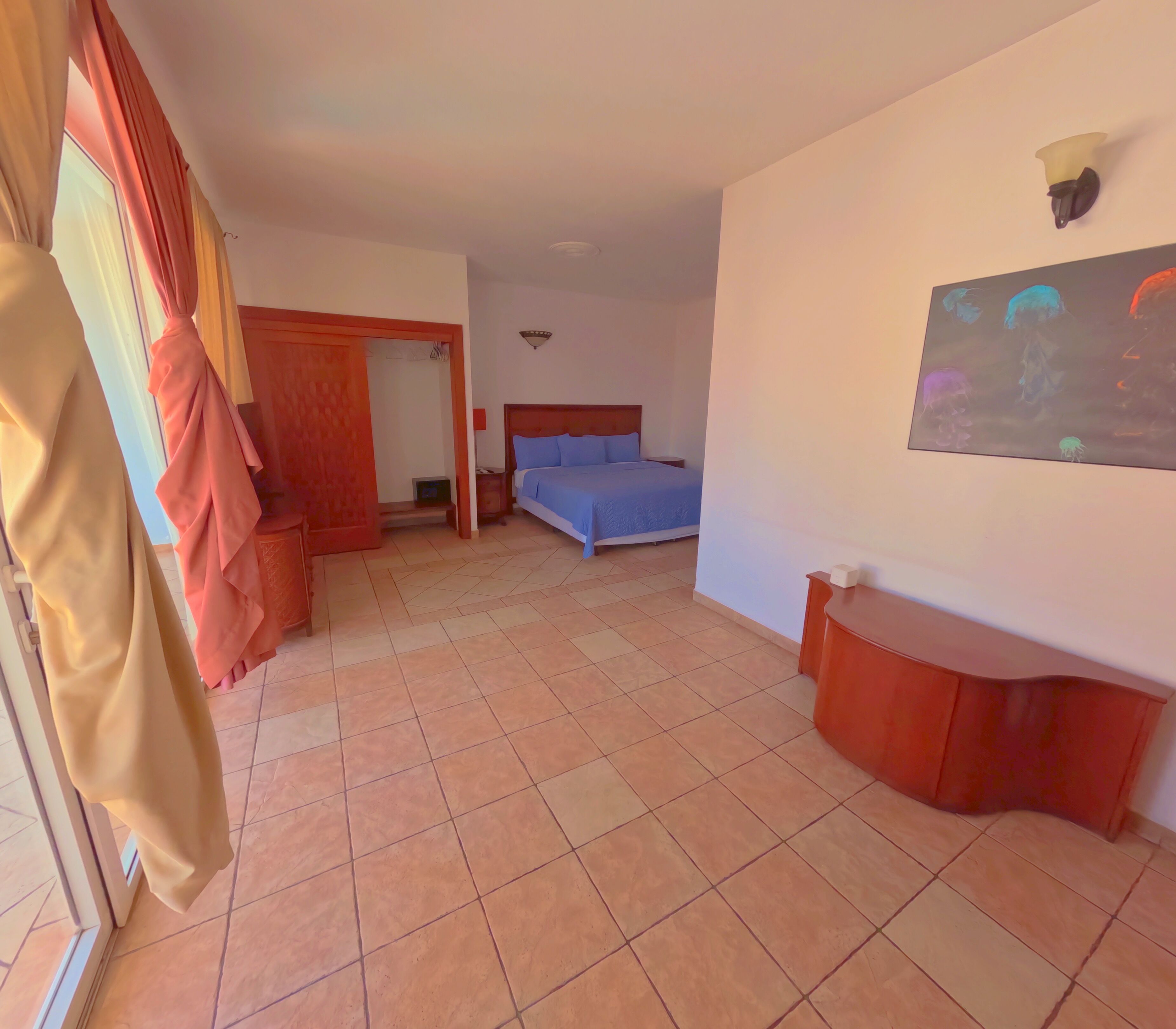 A hotel room with a bed, a nightstand, a wall-mounted lamp, and a painting.
