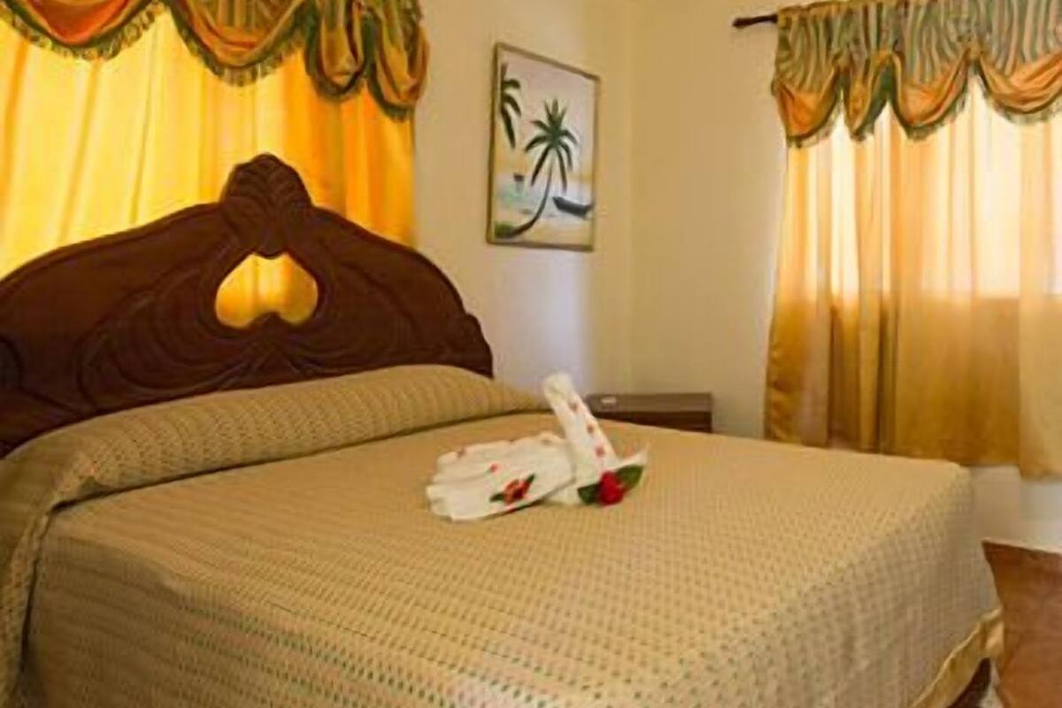 A neatly made bed with a floral pillow and a white towel.