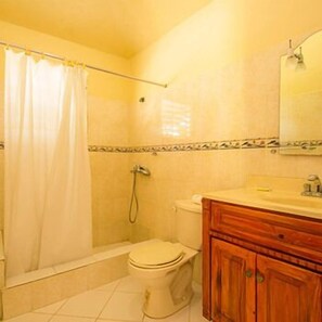 A bathroom with a bathtub, toilet, and wooden vanity.