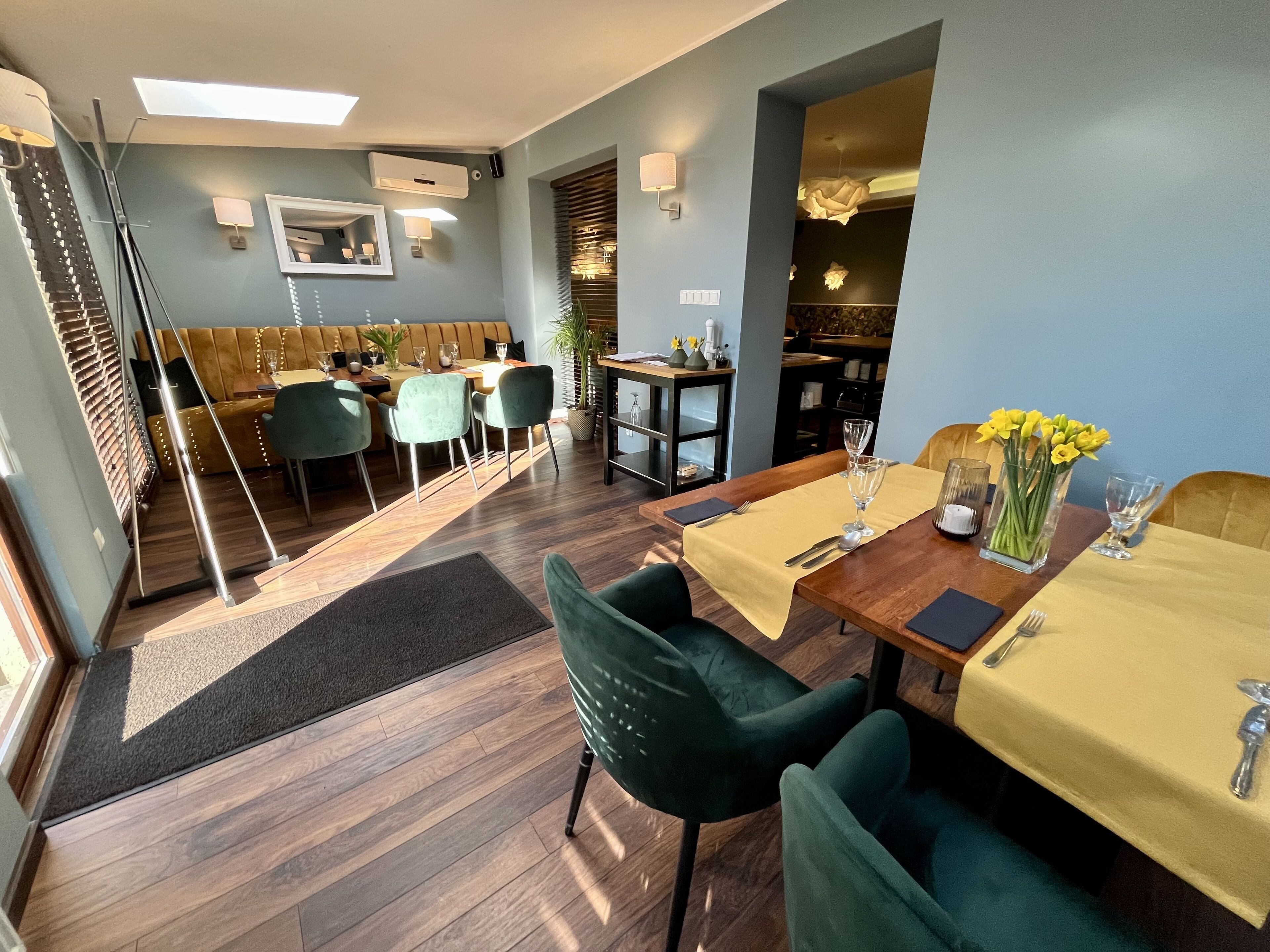 Un coin repas avec une table en bois, des chaises et une nappe jaune. Un vase rempli de fleurs jaunes est posé sur la table.