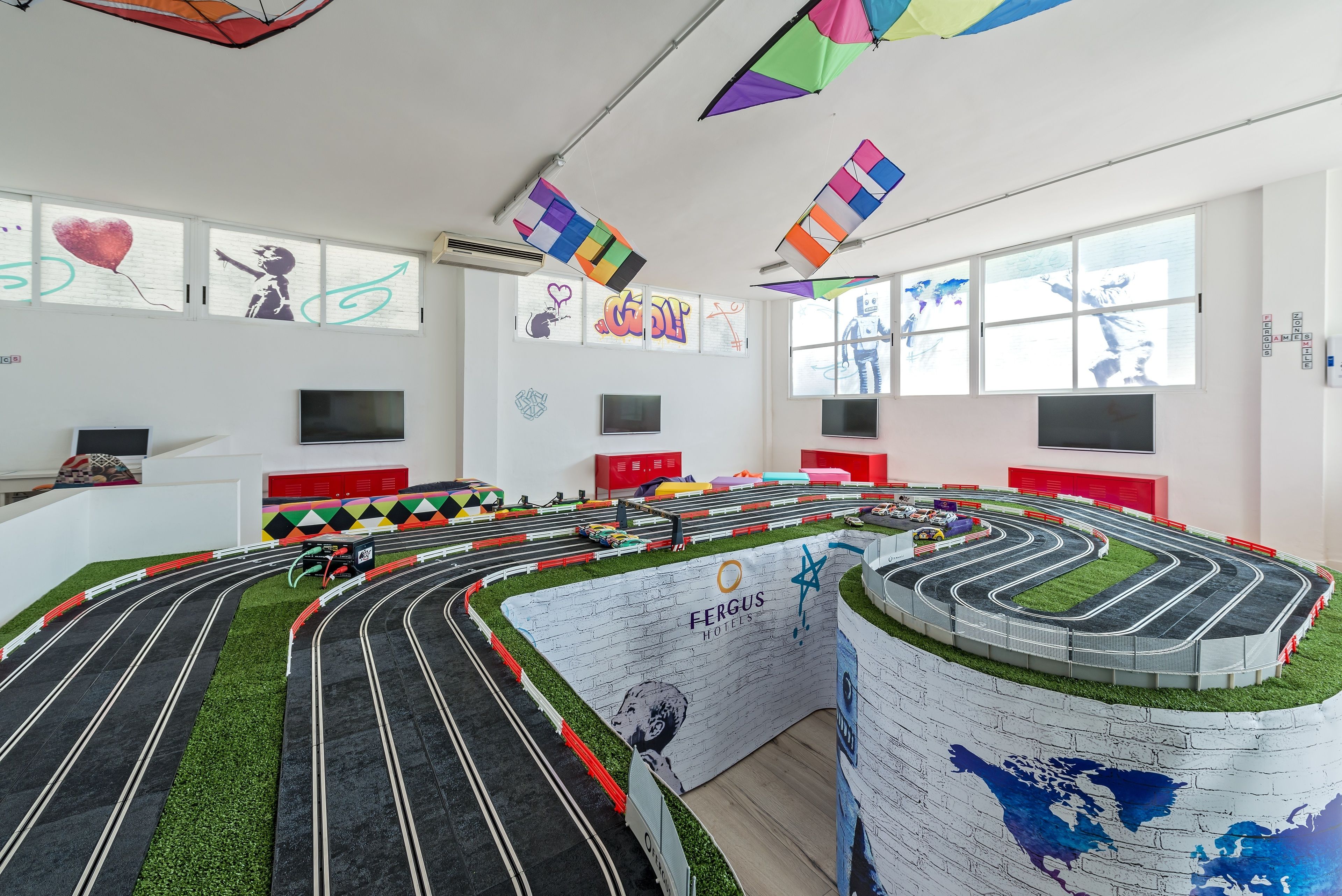 Una pista de carreras modelo con noria y un mural de un mapa mundial.